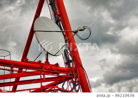 Part of communication tower with satellite dish against backdrop of dramatic sky with storm clouds. Telecommunication tower close-up. 96210636