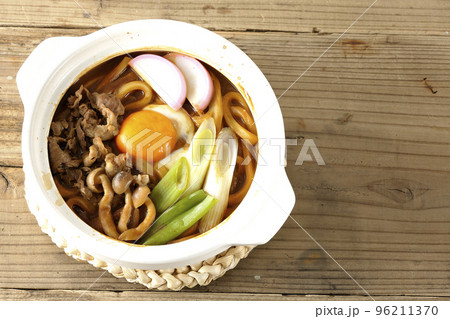 牛肉、しめじ、長葱、カマボコ、卵黄が入っている味噌煮込みうどんを俯瞰で撮影 96211370