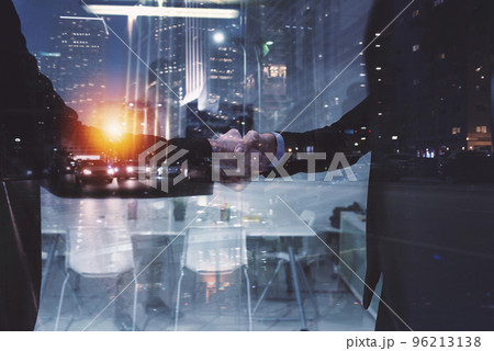 Handshaking business person in office. concept of teamwork and partnership. double exposure Handshaking business person in office. concept of teamwork and partnership. double exposure 96213138
