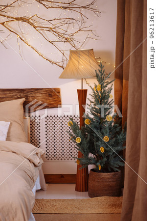 Beautiful decorated Christmas tree with fairy lights in bedroom interior Beautiful decorated Christmas tree with fairy lights in bedroom interior 96213617