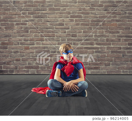 Superhero kid sitting on a wall that dreams Superhero kid sitting on a wall that dreams 96214005