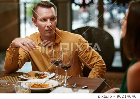 Man talking to wife when eating dinner in restaurant 96214646