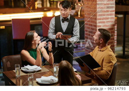Woman asking waiter to recommend her dish when eating in restaurant Woman asking waiter to recommend her dish when eating in restaurant 96214793