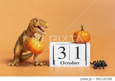 Toy dinosaur Tyrannosaurus, pumpkin, Calendar date 31 October, spider isolated on orange background Holiday greeting card Happy Halloween day creative minimal concept. Toy dinosaur Tyrannosaurus, pumpkin, Calendar date 31 October, spider isolated on orange background Holiday greeting card Happy Halloween day creative minimal concept. 96216166
