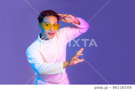 Young asian man in white long sleeve t-shirt wearing vr goggles watching playing and touching blue color background. Metaverse concept... Young asian man in white long sleeve t-shirt wearing vr goggles watching playing and touching blue color background. Metaverse concept... 96216509