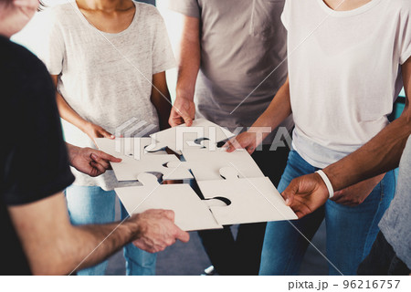 Team of young businessmen combine pieces of puzzle. Concept of integration and partnership Team of young businessmen combine pieces of puzzle. Concept of integration and partnership 96216757