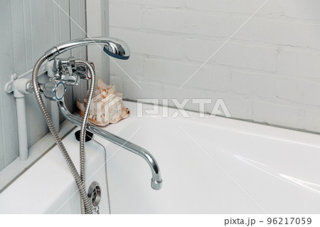 Bathroom with a shiny faucet, shower, white bathtub and a shell in the corner 96217059
