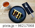 creative food design concept, top view, dark blue plate, cup of tea, fork, cake. 96217068