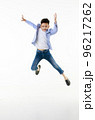 A 10-year-old Asian boy in a casual jacket is jumping smartly and happily looking at the camera against a white isolate background. 96217262