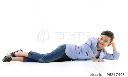 A 10-year-old Asian boy in a casual jacket is lying on the floor and smiling happily in a good mood looking at the camera. Positive concepts for children and young men's lifestyles. 96217403
