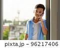 A young boy, an Asian elementary school student, is holding a smartphone calling and talking to someone. 96217406