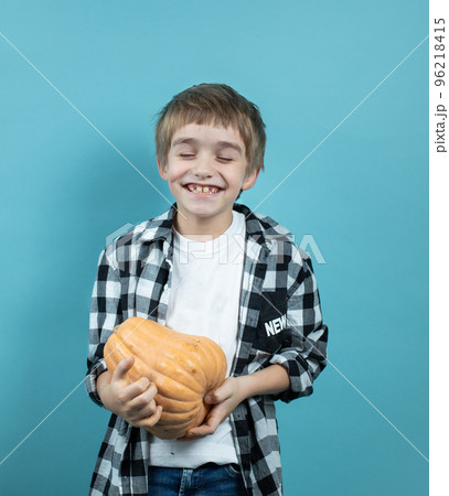 A good harvest. Portrait of a smiling guy with a pumpkin in his hands. Blue background,copy of the space 96218415