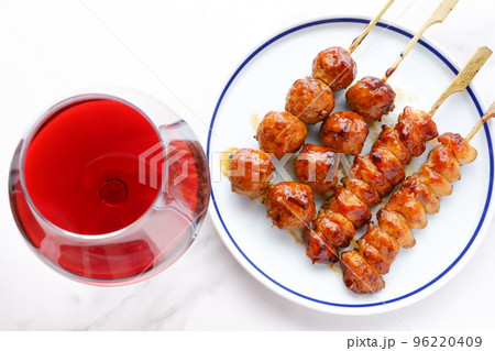 炭火でじっくり焼き上げた焼き鳥（タレ）と赤ワインのグラス 96220409