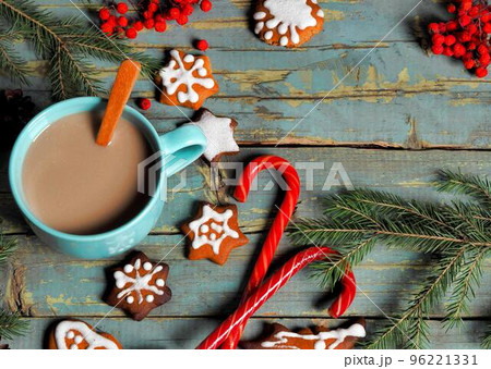 Blue cup with coffee, gingerbread cookies, spruce branches and cones on an old wooden background. Christmas retro food background.Place for text. Banner 96221331