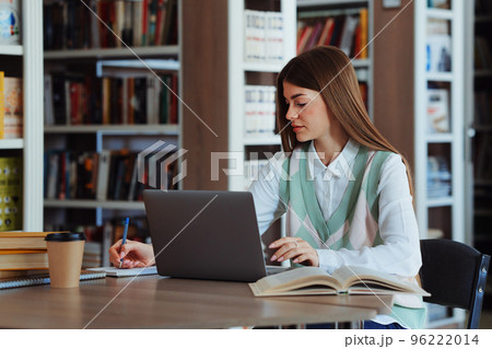 Female student using laptop in college library 96222014