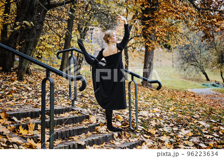 Ballerina Dancing in autumn city street, Modern Ballet Dancer in black dress, Pointe Shoes outdoors. Ballerina stretches, daily ballet stretching routine 96223634