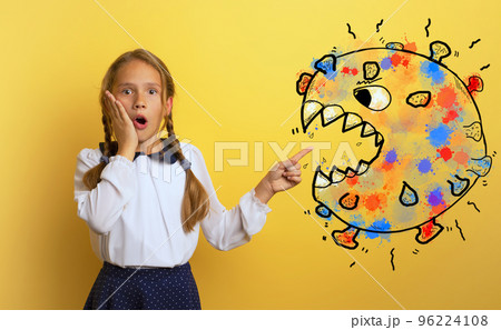 Young student is with shocked expression and indicates covid-19 bacteria. Yellow background. 96224108