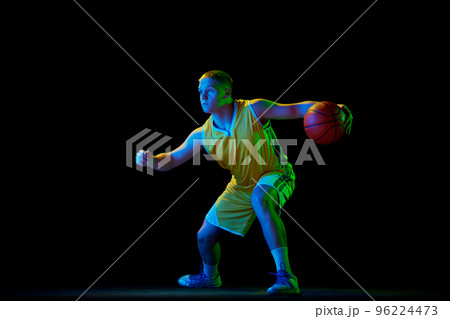 Professional basketball player in action with ball isolated on black background in neon light filter. Dribbling. Sport, energy, skills, team competition Professional basketball player in action with ball isolated on black background in neon light filter. Dribbling. Sport, energy, skills, team competition 96224473