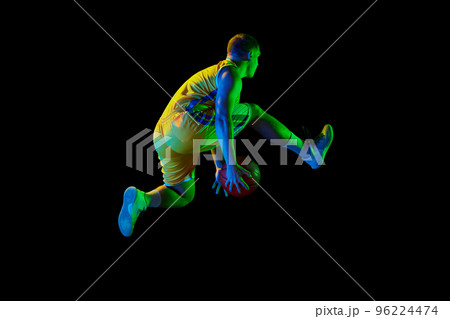 Active athletic male basketball player jumping with basketball ball isolated over dark background in blue neon light. Concept of energy, professional sport, hobby. Active athletic male basketball player jumping with basketball ball isolated over dark background in blue neon light. Concept of energy, professional sport, hobby. 96224474