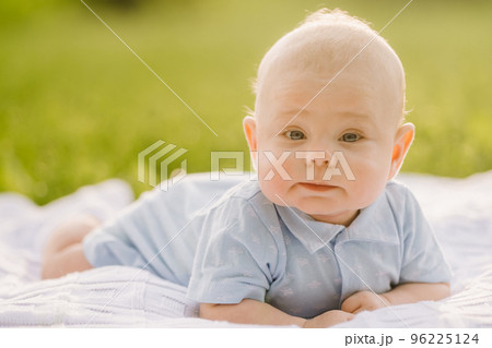 Cute happy toddler lying on a blanket on the grass outdoors in summer Cute happy toddler lying on a blanket on the grass outdoors in summer 96225124
