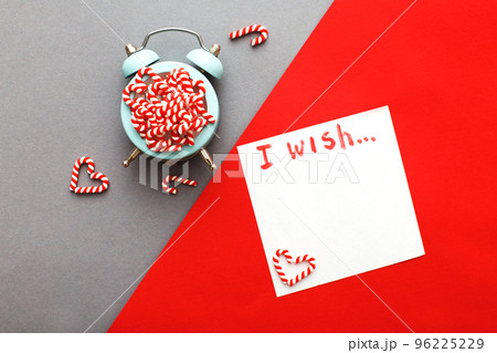 Christmas background with candy canes on alarm clock on gray and red background Christmas background with candy canes on alarm clock on gray and red background 96225229