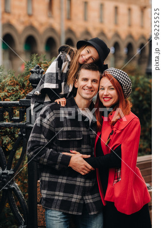 A stylish family of three strolls through the autumn city posing for a photographer . Dad, mom and daughter in the autumn city A stylish family of three strolls through the autumn city posing for a photographer . Dad, mom and daughter in the autumn city 96225525