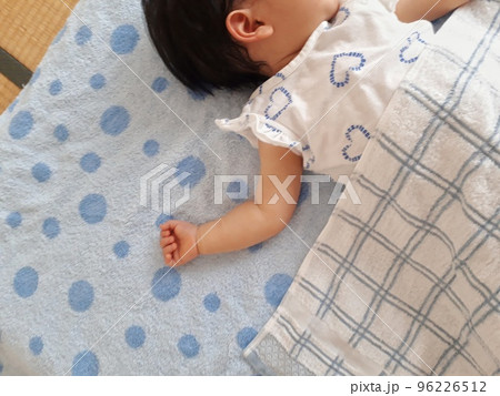 おなかにタオルをかけて仰向けで眠る小さな子ども 96226512