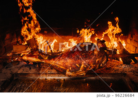 The lamb is cooked entirely on a spit on the fire. Cooking 96226684