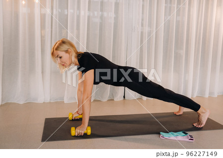 a woman in black sportswear is doing fitness with dumbbells in her hands. Sports, health, gymnastics and lifestyle concept 96227149
