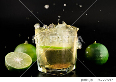 Shot of golden Mexican tequila with lime and salt on black background. A glass of tequila with lemon slices and splashing. Alcoholic drink concept. selective focus. Shot of golden Mexican tequila with lime and salt on black background. A glass of tequila with lemon slices and splashing. Alcoholic drink concept. selective focus. 96227347