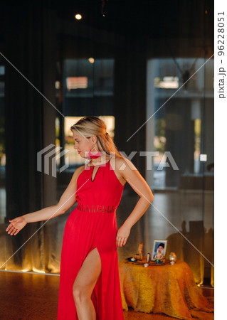 A girl in a red dress moves in a dance meditating indoors . Dynamic dance A girl in a red dress moves in a dance meditating indoors . Dynamic dance 96228051