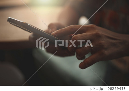 Close-up of woman's hand using a smartphone during coffee break. Close-up of woman's hand using a smartphone during coffee break. 96229453