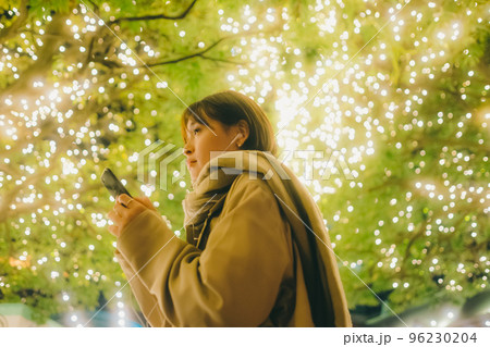 クリスマスの日に音楽を聴きながら待ち合わせをしている女性の写真 クリスマスの日に音楽を聴きながら待ち合わせをしている女性の写真 96230204