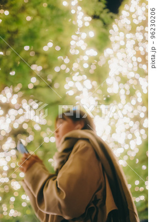 クリスマスの日に音楽を聴きながら待ち合わせをしている女性の写真 クリスマスの日に音楽を聴きながら待ち合わせをしている女性の写真 96230206