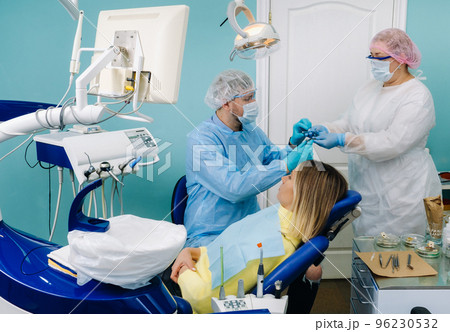A female patient in dental glasses treats teeth at the dentist with ultraviolet light. dental fillings A female patient in dental glasses treats teeth at the dentist with ultraviolet light. dental fillings 96230532