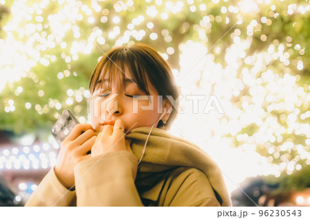 クリスマスの日に音楽を聴きながら待ち合わせをしている女性の写真 クリスマスの日に音楽を聴きながら待ち合わせをしている女性の写真 96230543
