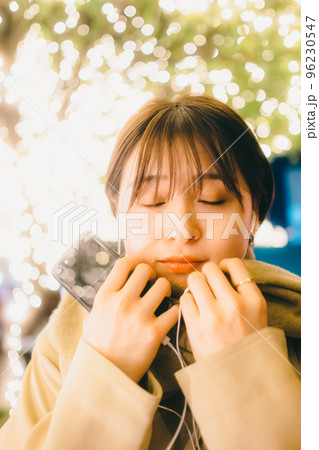 クリスマスの日に音楽を聴きながら待ち合わせをしている女性の写真 クリスマスの日に音楽を聴きながら待ち合わせをしている女性の写真 96230547