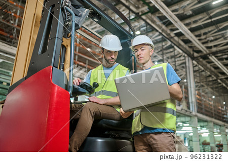 Men in protective helmets working in a storage area Men in protective helmets working in a storage area 96231322