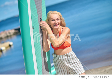 Smiling blonde woman on the beach looking contented Smiling blonde woman on the beach looking contented 96231497