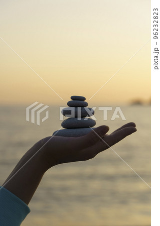 Zen stones background. Tower of stones on the sea beach on a summer evening. Meditation, calmness, peace, mental health concept. Zen stones background. Tower of stones on the sea beach on a summer evening. Meditation, calmness, peace, mental health concept. 96232823