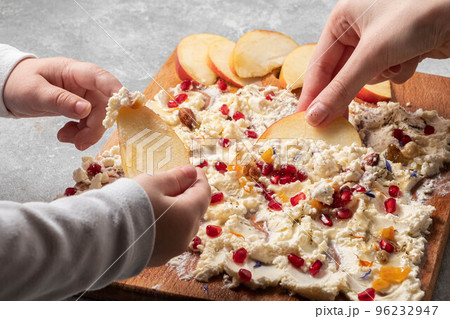Trendy sweet butter board. Children's hands hold apple slices over the Trendy sweet butter board. Children's hands hold apple slices over the 96232947