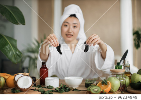 Focus on hands of smiling asian woman holding collagen patches Focus on hands of smiling asian woman holding collagen patches 96234949