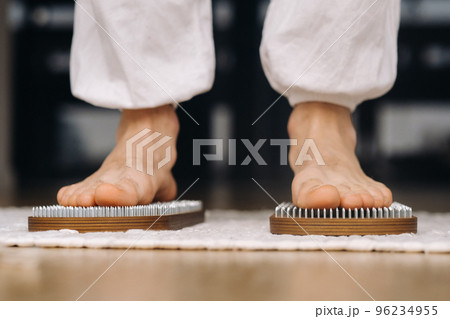 The man's feet are next to boards with nails. Yoga classes 96234955