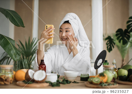 Happy asian woman holding bowl applying white mask homemade moisturizing and nourishing face mask 96235027