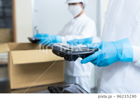 ダンボールに食品を詰める調理スタッフ　給食センター　弁当屋 96235290