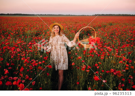 a girl in a dress with a hat and with a basket in a field with poppies a girl in a dress with a hat and with a basket in a field with poppies 96235313
