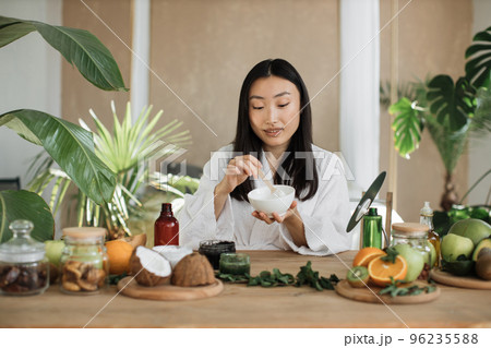 Beautiful healthy asian woman mixing the mass in a bowl while preparing cream. Beautiful healthy asian woman mixing the mass in a bowl while preparing cream. 96235588