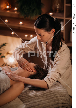 A cosmetologist girl does a facial and neck massage to a girl in the office for skin elasticity A cosmetologist girl does a facial and neck massage to a girl in the office for skin elasticity 96236023