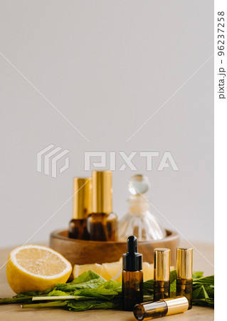 Essential oil in bottles with lemon and mint fragrance lying on a wooden surface Essential oil in bottles with lemon and mint fragrance lying on a wooden surface 96237258