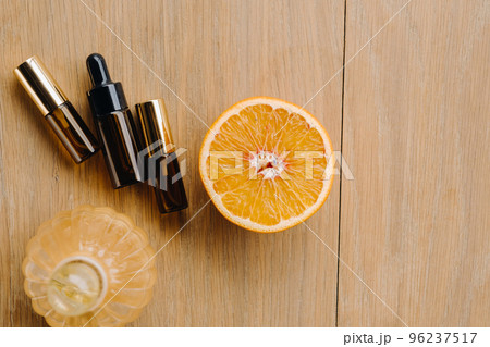 Essential oil in one bottle and orange slices lying on the surface 96237517